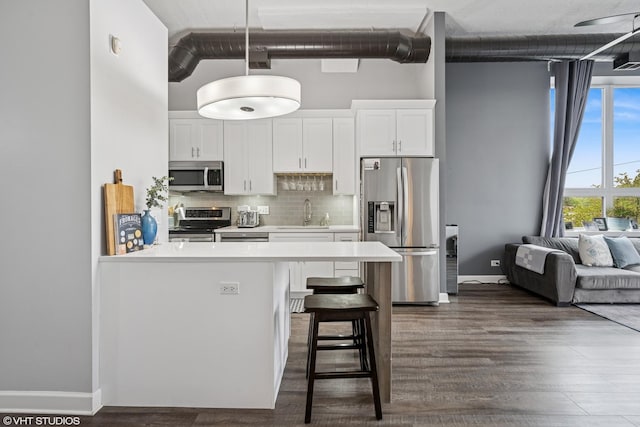 kitchen with a breakfast bar area, stainless steel appliances, a towering ceiling, backsplash, and light countertops