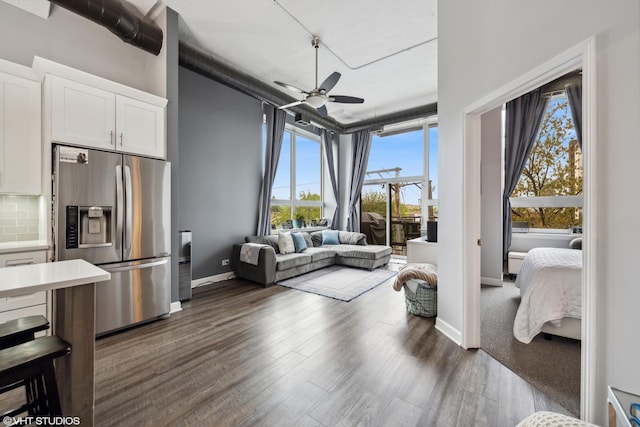 living room with baseboards, ceiling fan, and dark wood-style floors