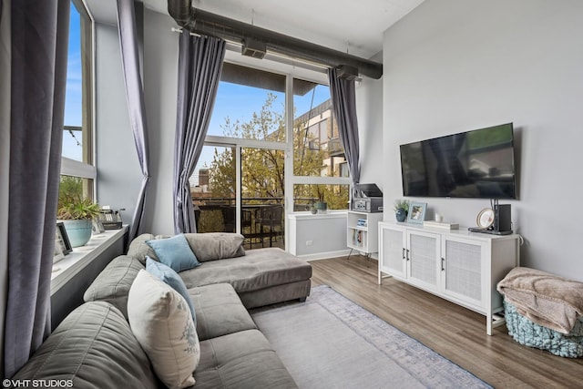 living area with floor to ceiling windows, a towering ceiling, and wood finished floors