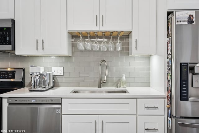 kitchen with a sink, light countertops, white cabinets, and appliances with stainless steel finishes