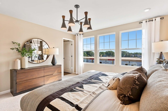 bedroom with baseboards, light carpet, and ceiling fan with notable chandelier