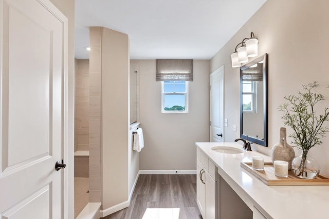 full bathroom featuring vanity, baseboards, a tile shower, and wood finished floors