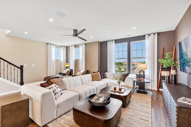 living area featuring light wood-style floors, ceiling fan, stairway, and a wealth of natural light