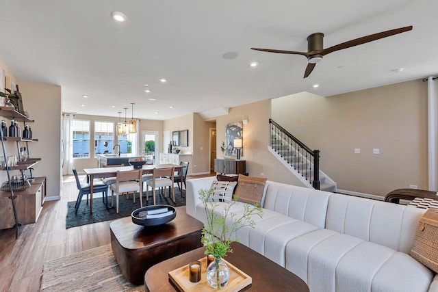 living area with ceiling fan, stairway, baseboards, light wood-style floors, and recessed lighting