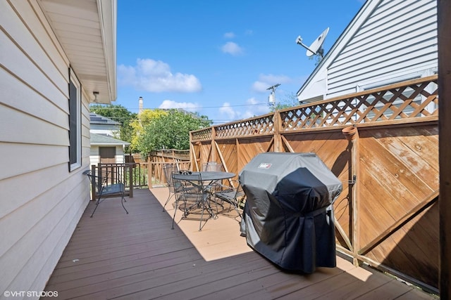 wooden terrace featuring area for grilling and outdoor dining space