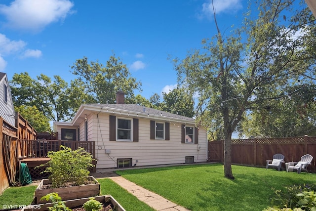 exterior space with a garden, a chimney, a front yard, a deck, and a fenced backyard