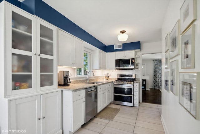 kitchen with visible vents, appliances with stainless steel finishes, a sink, light stone counters, and white cabinets