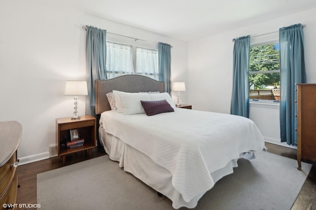 bedroom with baseboards, wood finished floors, and visible vents