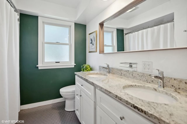 bathroom with a sink, baseboards, tile patterned flooring, and toilet