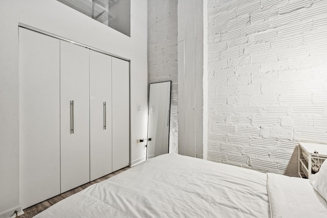 bedroom with a high ceiling, a closet, and wood finished floors