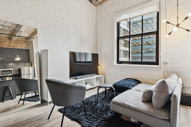 living room with a high ceiling, a healthy amount of sunlight, and light wood-style flooring