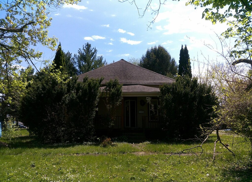exterior space with roof with shingles, a yard, and covered porch