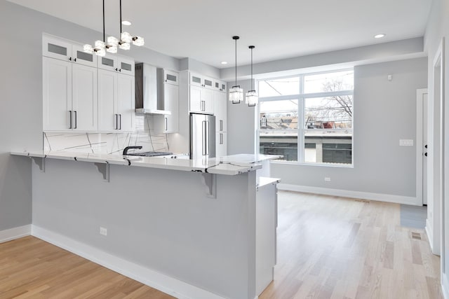 3450 N Central Ave, Chicago, IL 60634 - kitchen featuring wall chimney exhaust hood, high quality fridge, a breakfast bar, a peninsula, and light wood finished floors
