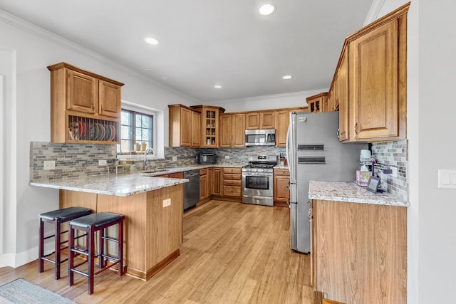 118 Jack Dylan Dr, Hampshire, IL 60140 - kitchen featuring brown cabinetry, crown molding, light wood finished floors, a peninsula, and stainless steel appliances