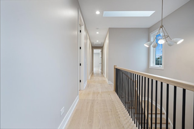 corridor with baseboards, recessed lighting, light wood-style flooring, and a skylight