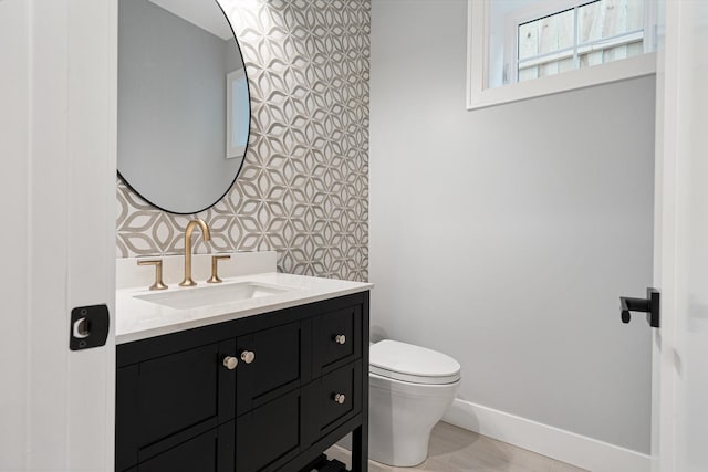 bathroom with vanity, baseboards, and toilet