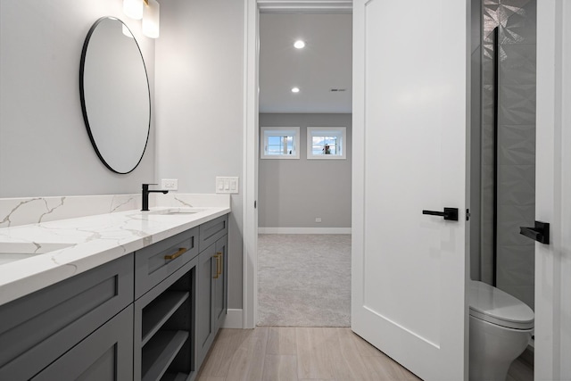bathroom featuring toilet, baseboards, recessed lighting, and vanity