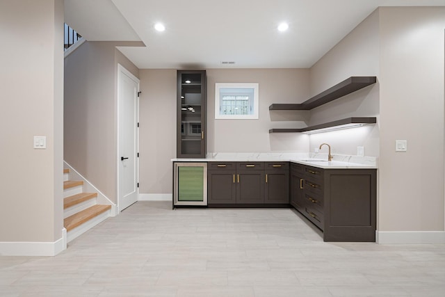 bar featuring recessed lighting, baseboards, a sink, and stairway