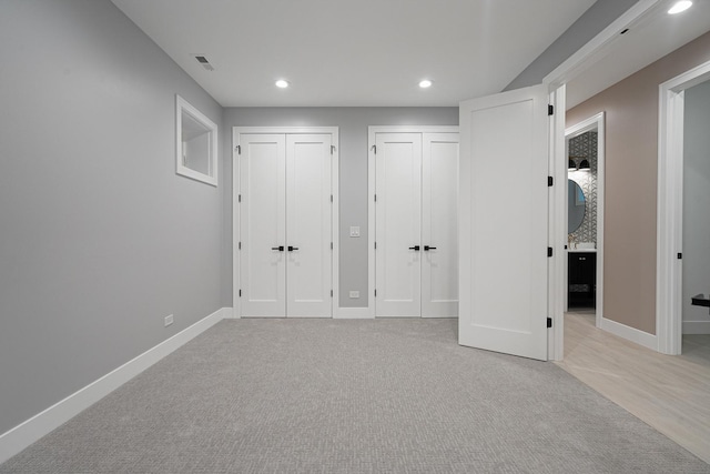 unfurnished bedroom with baseboards, two closets, recessed lighting, and light colored carpet