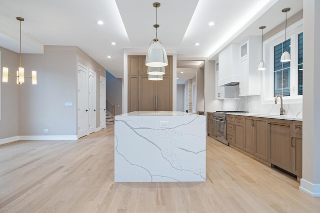kitchen with high end stainless steel range, a sink, light wood-style floors, a center island, and glass insert cabinets