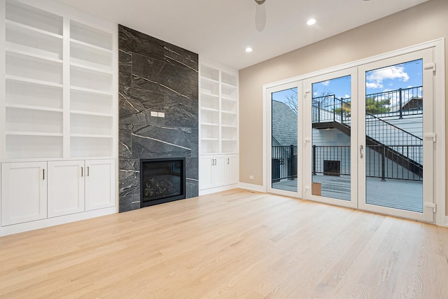 unfurnished living room with recessed lighting, built in features, wood finished floors, and a high end fireplace