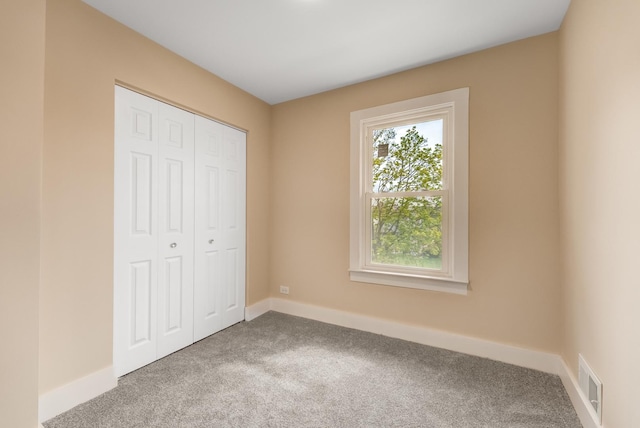 unfurnished bedroom with carpet floors, baseboards, visible vents, and a closet