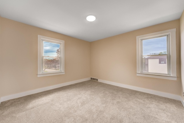 spare room featuring carpet flooring, baseboards, and visible vents