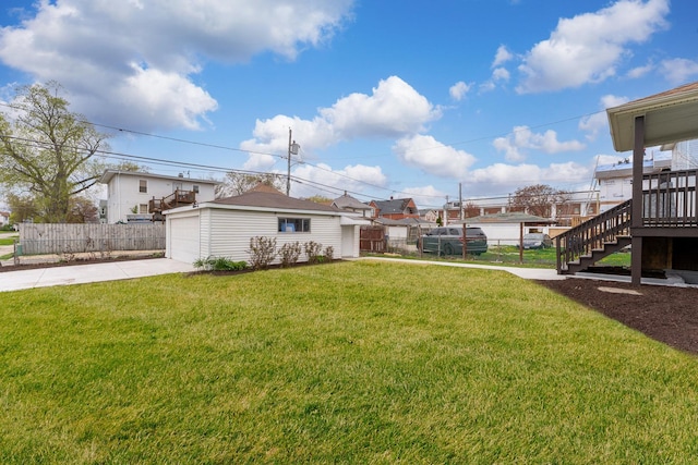 view of yard with a garage, fence, stairs, concrete driveway, and an outbuilding
