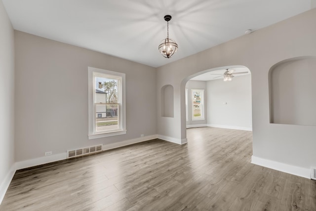 spare room with arched walkways, visible vents, plenty of natural light, and wood finished floors