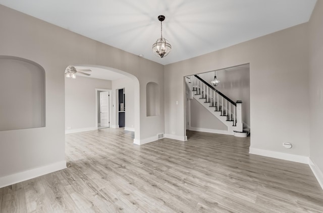 interior space with stairway, arched walkways, baseboards, and wood finished floors