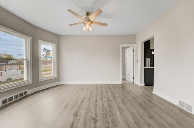 spare room with a ceiling fan, baseboards, visible vents, and light wood-style floors