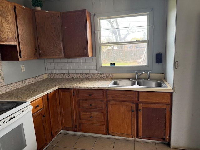 kitchen with light countertops, light tile patterned flooring, a sink, and electric stove