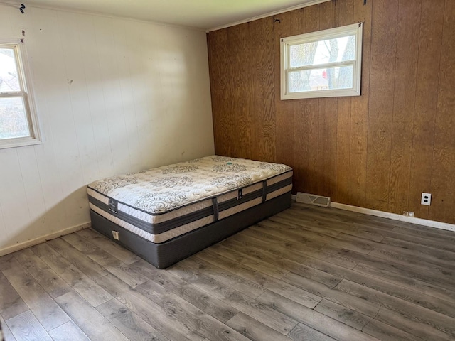 bedroom featuring wooden walls, hardwood / wood-style flooring, and visible vents