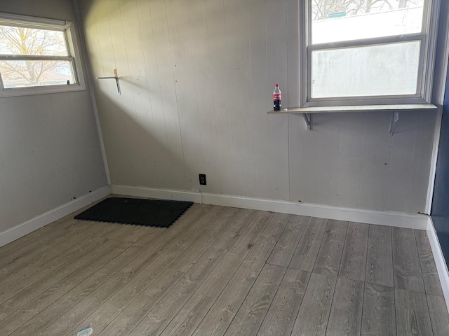 spare room with baseboards and wood-type flooring