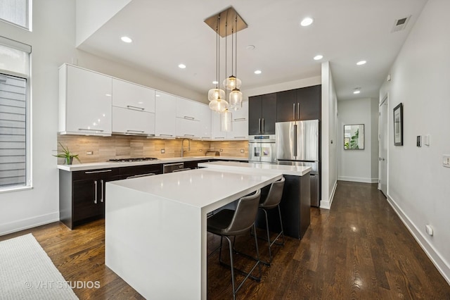 2109 N Campbell Ave Unit 2N, Chicago, IL 60647 - kitchen featuring stainless steel appliances, decorative backsplash, light countertops, baseboards, and a kitchen island