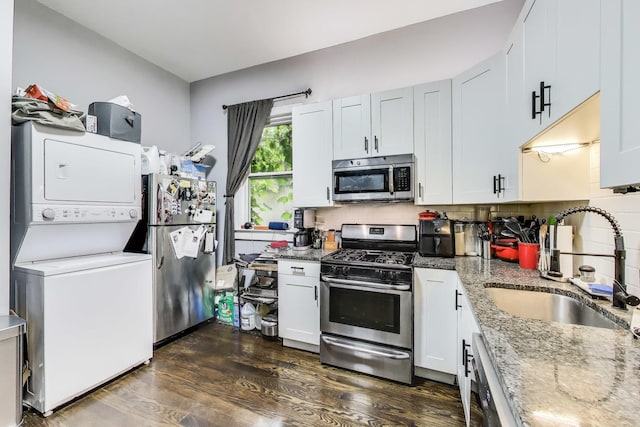 2437 W Taylor St, Chicago, IL 60612 - kitchen featuring stainless steel appliances, stacked washer / dryer, dark wood-style floors, light stone countertops, and tasteful backsplash