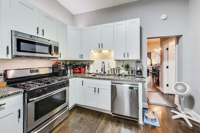 2437 W Taylor St, Chicago, IL 60612 - kitchen featuring stainless steel appliances, dark wood-style flooring, dark stone countertops, backsplash, and white cabinetry