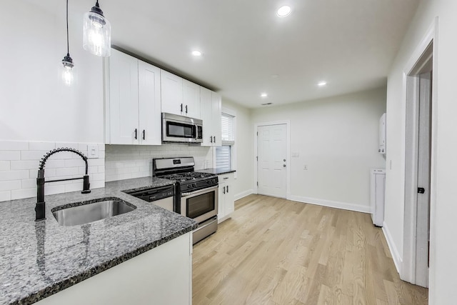 2437 W Taylor St, Chicago, IL 60612 - kitchen with stainless steel appliances, dark stone countertops, white cabinetry, decorative backsplash, and light wood-style floors