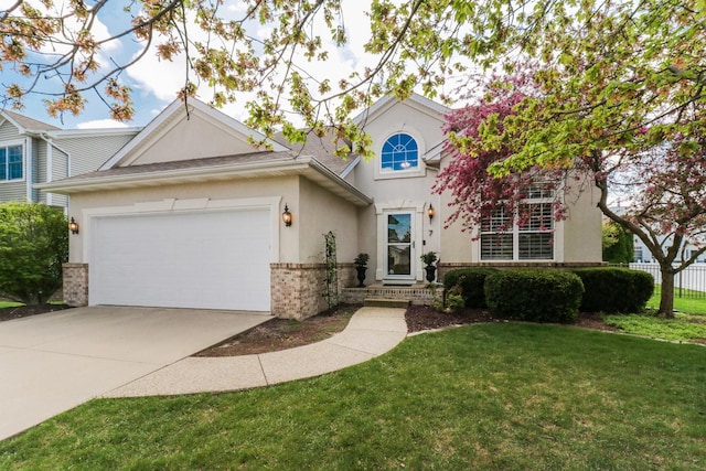 traditional home featuring a front yard, stucco siding, brick siding, an attached garage, and driveway