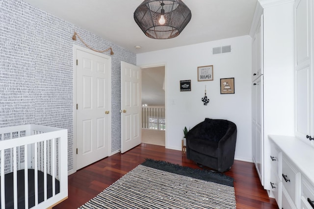 bedroom with baseboards, visible vents, and wood finished floors