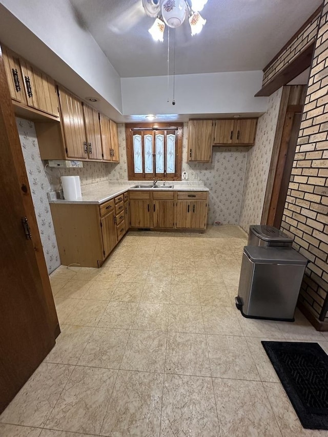 kitchen with brown cabinets, wallpapered walls, a sink, and light countertops