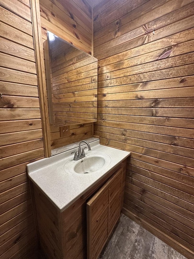 bathroom featuring wooden walls, wood finished floors, and vanity