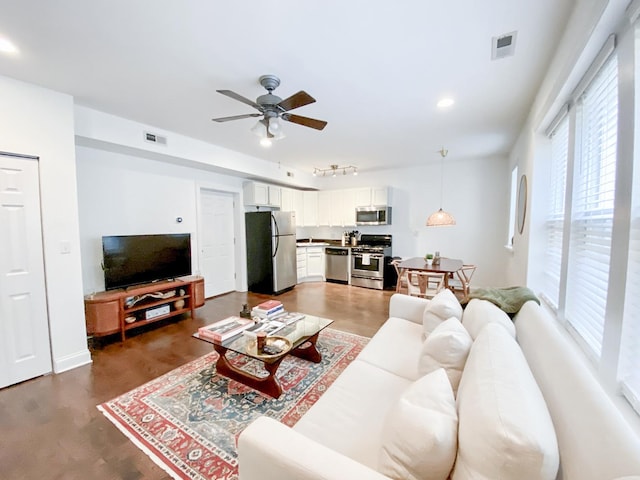 living area with visible vents, a ceiling fan, wood finished floors, and track lighting