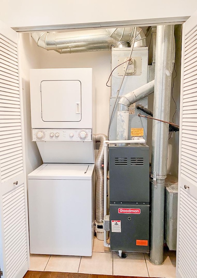 laundry room featuring light tile patterned flooring, stacked washer / drying machine, and laundry area