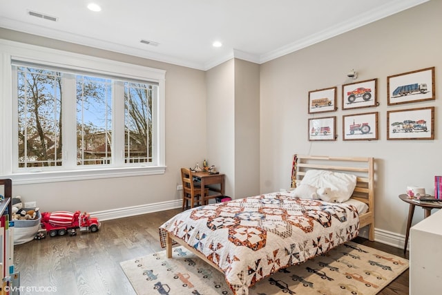 bedroom with baseboards, visible vents, ornamental molding, and wood finished floors