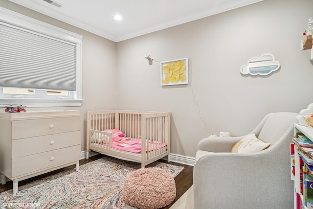 bedroom with a nursery area, recessed lighting, baseboards, wood finished floors, and ornamental molding