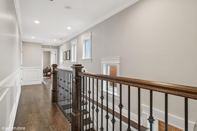 hall featuring crown molding, dark wood finished floors, a wainscoted wall, an upstairs landing, and a decorative wall