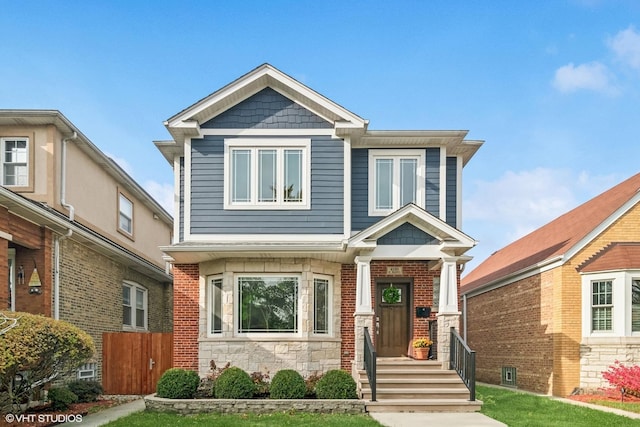 craftsman-style house with fence and stone siding