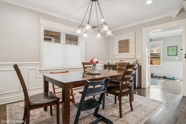 dining area featuring wainscoting, dark wood-style floors, ornamental molding, and a decorative wall