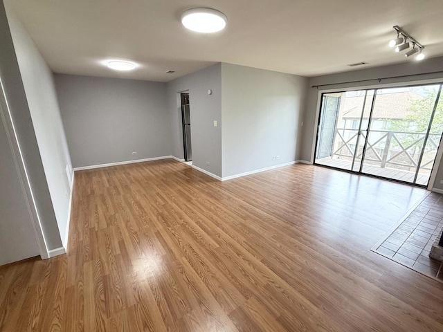 unfurnished room featuring light wood-type flooring, baseboards, and visible vents
